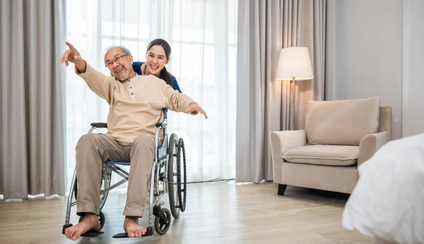 若い女性看護師と楽しい車椅子に座っているアジアの高齢者引退した男性 幸せなキュレーター人の医師プッシュし 高齢者の患者の自由を実行して腕を上げ 療養所 — ストック写真