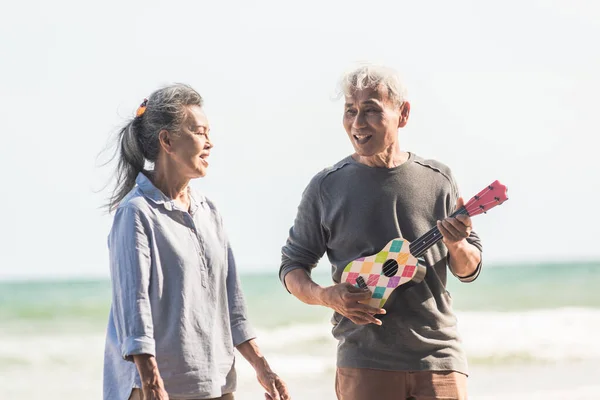 노부부 야외에서 노래를 부르고 해변에서 어쿠스틱 기타를 연주하는 해수욕장에서 아내를 — 스톡 사진