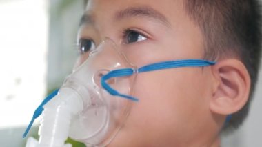 Asian Child using nebulizer mask equipment alone have smoke, Kid boy making makes inhalation nebulizer steam sick cough at home, oxygen spray inhaler therapy, stuffy nose and runny, Health medical