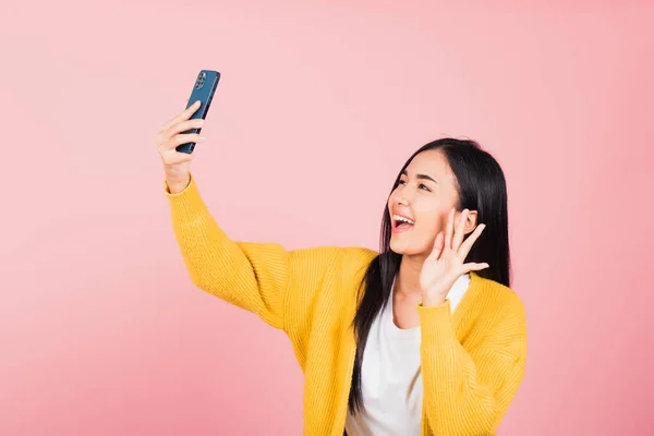 幸せなアジアの肖像画美しいかわいい若い女性が笑顔興奮して自撮り写真を作る ピンクの背景に隔離されたスマートフォンのスタジオショットでビデオ通話 女性は携帯電話を保持手を上げると言うこんにちは — ストック写真