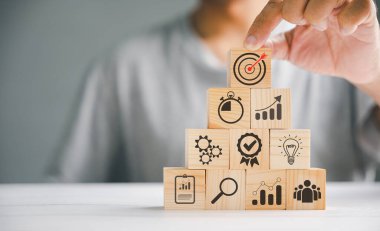 Elle düzenlenmiş tahta blok yığını iş stratejisini ve eylem planını gözler önüne seriyor. Hedef ve hedef simgeleri başarıyı ve başarıyı simgeler. Kopyalama alanı dahil.