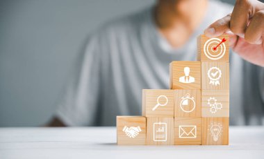 Tahta blokların elle istiflenmesi, bir iş stratejisi ve eylem planının uygulanmasını sembolize ediyor. İş konseptini hedefliyorum. Büyümenin ve başarının kavramsal görüntüsü.
