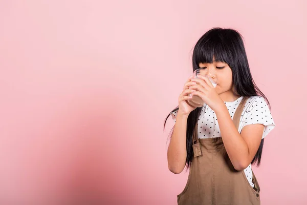アジアの小さな子供10歳の笑顔を保持ミルクグラスドリンク白ミルクとスタジオで飲むピンクの背景に隔離されたショット 幸せな子供の女の子の日常生活医療医学食品 — ストック写真