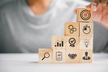 Tahta blokların elle istiflenmesi, bir iş stratejisi ve eylem planının uygulanmasını sembolize ediyor. İş konseptini hedefliyorum. Boşluğu kopyala.