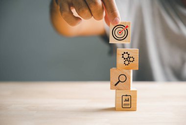 İşadamları ahşap blokları titizlikle düzenliyor, bir iş stratejisi ve eylem planı çiziyor. Bu görüntü iş geliştirme ve başarı kavramını temsil eder..