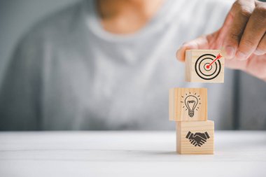 Tahta blokların elle istiflenmesi bir iş stratejisi ve eylem planının uygulanmasını sembolize ediyor. İş konseptini hedefliyorum. Başarı ve büyümenin kavramsal görüntüsü.