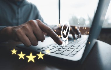 İşadamı ISO sertifikası ve kalite güvencesi simgesi gösteren dizüstü bilgisayar kullanıyor. Standartlara uyma ve tatmin garantisi. Modern teknoloji aygıtı anahtar.