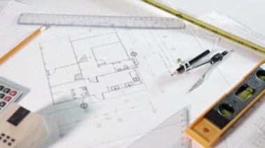 Mimari proje işyeri. Mimarlık bürosundaki masa başında tamir aletleri olan ev planı tasarım kağıtlarının üst görünümü, Mühendislik mimari tasarım araçları konsepti