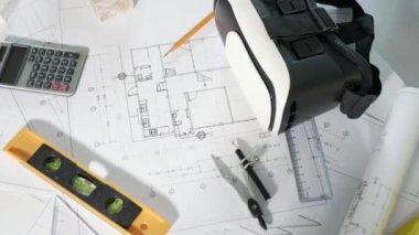 Mimari işyeri üst görünümü. Mimari proje planları masa üzerinde, mühendislik müteahhitlerinin tasarım için araç çalışma çizimi ve VR gözlükleri, sanayi sanal teknolojisi