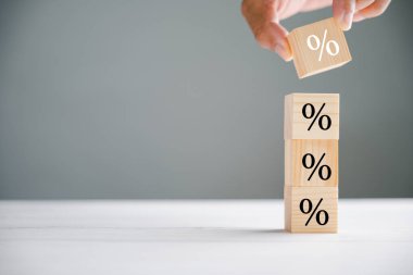 Göze çarpan görüntü faiz oranı ve ipotek oranlarını yakalıyor. İş adamlarının elleri yüzdelik sembol simgesiyle bir tahta küp bloğu koyarak oranların dalgalanan doğasını sembolize ediyor..