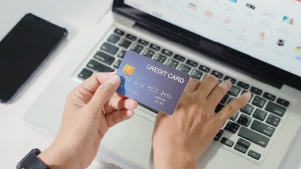オンラインショッピング 女性の手のトップビューは クレジットカードを保持し 自宅で製品の購入とラップトップを使用して 電子決済セキュリティをオンラインにするためにコンピュータ上のクレジットカードを介して女性のレジスタ — ストック動画