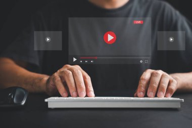 Dijital aktivitelere katılan bir adam çevrimiçi video izleyen, içeriği yayınlayan, sanal sınıflara katılan ve multimedya yaratan bir bilgisayar kullanıyor..