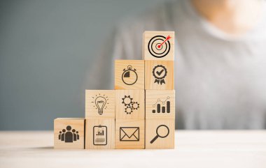 Tahta küp, Eylem Planı, Gol ve Hedef simgeleriyle bir masanın üzerine basar. Başarı ve iş hedefi konsepti. Proje yönetimi ve şirket stratejisi büyümeyi simgeliyor.