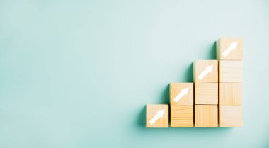 Merdiven kariyer yolu iş büyümesini ve başarıyı simgeliyor. Tahta bloklar yukarı doğru ok ile merdiven olarak dizilmiş. Daha yüksek gelir, hedefler, finans ve yatırım stratejileri yolunda ilerleme