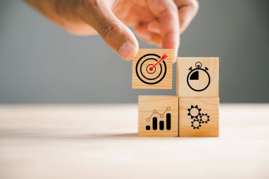 İş stratejisi ve Eylem Planı kavramını gözler önüne seren bir el tarafından yönetilen tahta bloklama. Takım işbirliği ve büyüme fikri hedefleniyor.