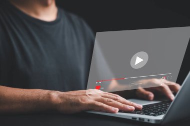 İşadamı bilgisayarındaki canlı yayından büyülenmiş. Ekranda multimedya oynatıcısı olan video yayını kavramı. Medya tüketimi için teknolojinin gücünü kucaklamak.
