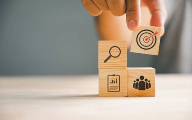 Stratejik bir iş planı ve eylem planını sembolize eden bir iş adamının rehberliğindeki tahta bloklama. İş dünyasında yükselen büyüme ve başarıyı temsil eder..