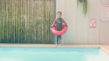 Mutlu çocuk yüzme havuzunda oynuyor, şişme yüzükte mutlu çocuk suya atlıyor ve yaz tatillerinde, tatillerde ve tatillerde, sağlıklı açık hava aktivitelerinde eğleniyor.