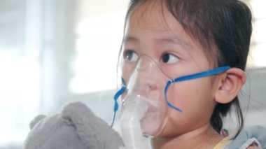 Kid girl making makes inhalation nebulizer steam sick cough at home, Asian Child using nebulizer mask equipment alone have smoke, stuffy nose and runny, oxygen spray inhaler therapy, Health medical