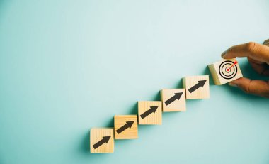 Tahta bloklar, belirgin bir hedef simgesi ve yükselen oklar. Çizelge çizelgesi mavi arka plandaki iş büyümesini gösteriyor. Kar, yatırım ve ekonomik gelişim kavramlarını temsil eder.