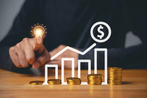 Creative ideas for saving money concept. Hand holding light bulb with coins stack and chart graph, representing money management for future and business accounting. symbol of growth
