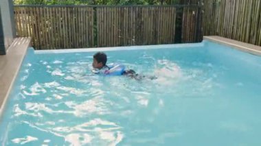 Mutlu genç, kıvırcık saçlı, şişme yüzüklü, suda eğlenen ve yaz tatilinde havuzda eğlenen mutlu çocuk, havuzda oynayan çocuk, yaz tatilleri ve tatil konsepti.