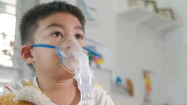 Asian Child using nebulizer mask equipment alone have smoke, Kid boy making makes inhalation nebulizer steam sick cough at home, oxygen spray inhaler therapy, stuffy nose and runny, Health medical