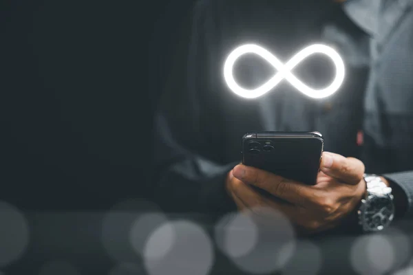 Businessman showcasing smartphone with infinity symbol, symbolizing unlimited connection in data technology, future unlimited. Infinite power, energy, internet information. technology infinity data