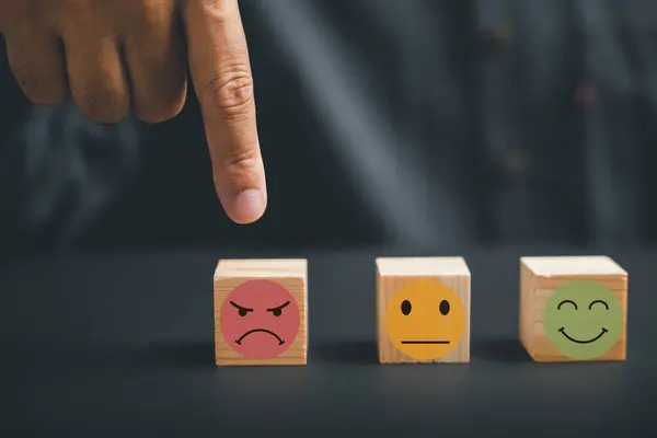 Unhappy customer expressing dissatisfaction with sad emoticon on wooden block. Concept of customer experience dissatisfaction, bad review and low rating. unsatisfied customers on business reputation.