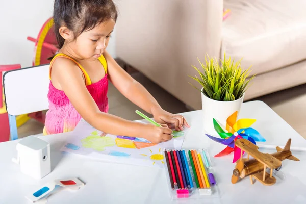 幸せな子供の女の子カラフルな絵の風景紙の上に私の家の夢 アジアのかわいい子供の未就学児は テーブルの上に座って笑顔彼女は芸術の宿題を学ぶために自宅で鉛筆でカントリーハウスの絵を描く — ストック写真