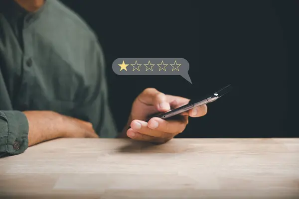 Unhappy client uses smartphone to give a 1-star satisfaction rating on social media. Negative feedback concept impacting business reputation and customer perception.