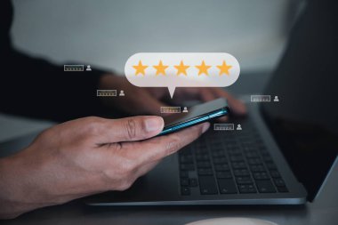 Akıllı telefon ve dizüstü bilgisayarı kullanarak hizmetleri değerlendiren ve değerlendiren bir adam, iyi bir geri bildirim değerlendirmesi için beş yıldızlı bir simge kullanıyor. Dijital pazarlama ile iş ve teknoloji kavramı