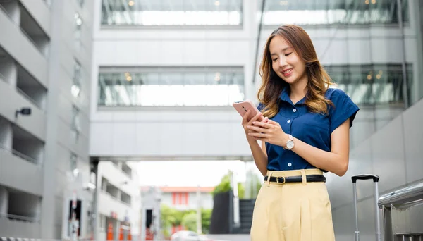 青いシャツを着ている女性が街の携帯電話で歩き テキストを送ります スマートフォンアプリを使用して オンラインで接続して買い物をする若い女の子 — ストック写真