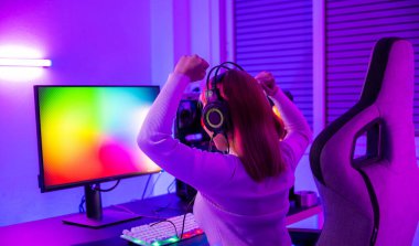 Winning Victory. Asian gamer playing online video game excited on desktop computer PC colorful neon LED lights, young woman in gaming headphones using computer she happy successful, E-Sport concept