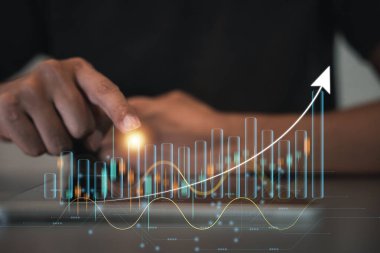 İş adamı, karanlık bir arkaplanı işaret eden bir okla holografik grafik grafik grafik ve çizelge sunuyor. Borsa büyümesi ve strateji kavramı. Anahtar, teknoloji ve veri analizi..