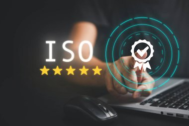 ISO sertifikası ve belge yönetim sistemini gösteren dizüstü bilgisayarı olan bir iş adamı. Kalite güvencesi ve standart uyum mevcut. İnternet güvenliği ile en üst düzey hizmet garantilidir.