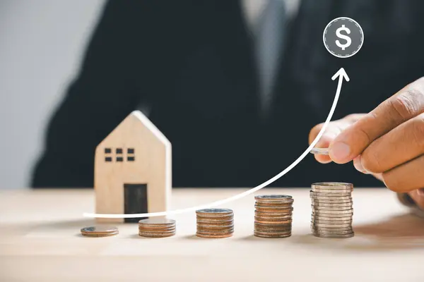 Investing in property hand places coins in a stack by a house. Real estate growth, mortgage finance theme. Secure your financial future through property investment. Property Taxes
