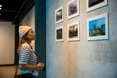 Fotoğraf çerçevesinde fotoğraf ziyaretinden sergi sergisi sanat galerisine doğru eğilmeye, Asyalı kadın resim galerisi koleksiyonuna kamera tutmaya, duvardaki çerçeveli resimlere ve