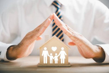 Aile sigortası ve bakım ideallerini taşıyorum. Aile silueti ile işadamı koruyucu jesti. Aile, yaşam, sağlık ve ev sigortası ikonları. Sigorta kavramı yakalanıyor.