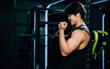 Spor salonunda kablo trisepsi yapan bir erkek sporcu kendini adadığını ve kaslı bir fiziği koruma çabasını gösteriyor. Yaşam tarzı ve insan konsepti
