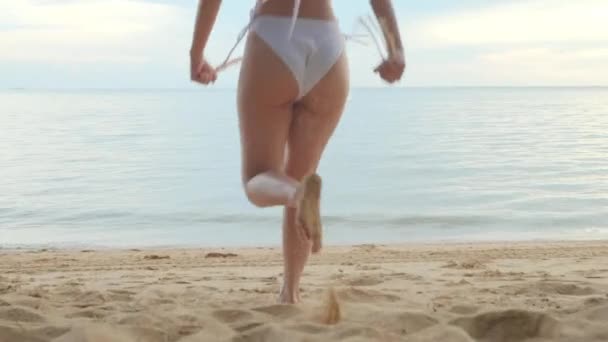 バックビュー 若い美しい女性を着てビキニ水着は 水に砂のビーチで熱帯に実行しています 幸せなアジアの女性は彼女が外で休日を実行する楽しみを持っています 夏の旅行休暇のコンセプト — ストック動画