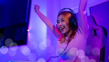 Kazanmak. Happy Gamer 'ın genç oyuncuları çevrimiçi bilgisayar oyunu oynuyorlar. Turnuvayı kazanmak için ellerini kaldırıyor. Oyun kulaklıkları takan genç bir kadın internette video oyunu oynuyor.