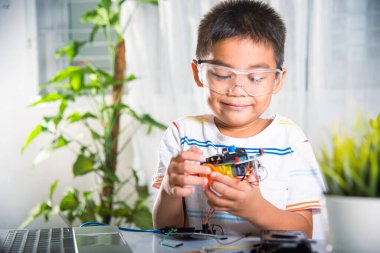 Little child trying assemble build wheel to car toy, Asian kid boy assembling wheel into Arduino robot car homework, creating electronic AI technology workshop online school lesson