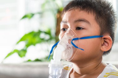 Asian Child using nebulizer mask equipment alone have smoke, Kid boy making makes inhalation nebulizer steam sick cough at home, oxygen spray inhaler therapy, stuffy nose and runny, Health medical