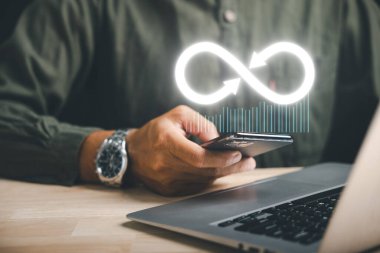 Businessman presents smartphone with infinity symbol, signifying limitless connection in data technology, future unlimited. Infinite power, energy, internet information. technology infinity data
