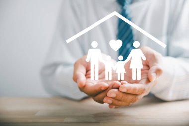 Aile refahını arttıran iş adamı koruyucu jesti genç aile silueti ile yankılanıyor. Sağlık ve ev sigortası ikonları, aile desteğini vurgulayarak güvenlik ve bakımın altını çizdi.