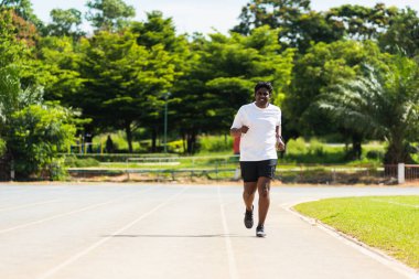 Asyalı genç yaşam tarzı atlet spor koşucusu siyahi adam koşu bandı yolunda açık havada ayakkabı giyip koşuyor, sağlıklı egzersiz yapıyor.