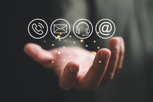 Contact us concept portrayed by hand holding phone, mail, and message icons. Customer service call center and feedback displayed on banner. Copy space available for communication, contact and feedback