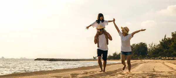 Family day. Happy family people having fun in summer vacation run on beach, daughter riding on father back and mother running at sand beach, family trip playing together outdoor, traveling in holiday