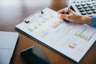 Belgeler, grafikler ve hesap makinesiyle çalışan Asyalı iş kadını, iş kağıt pazarlama istatistiği ve verileri üzerine yazan kadın muhasebeci, özet rapor muhasebe kavramı
